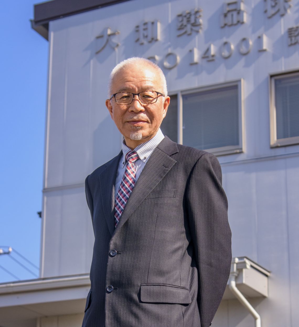 社屋を背にした社長の写真